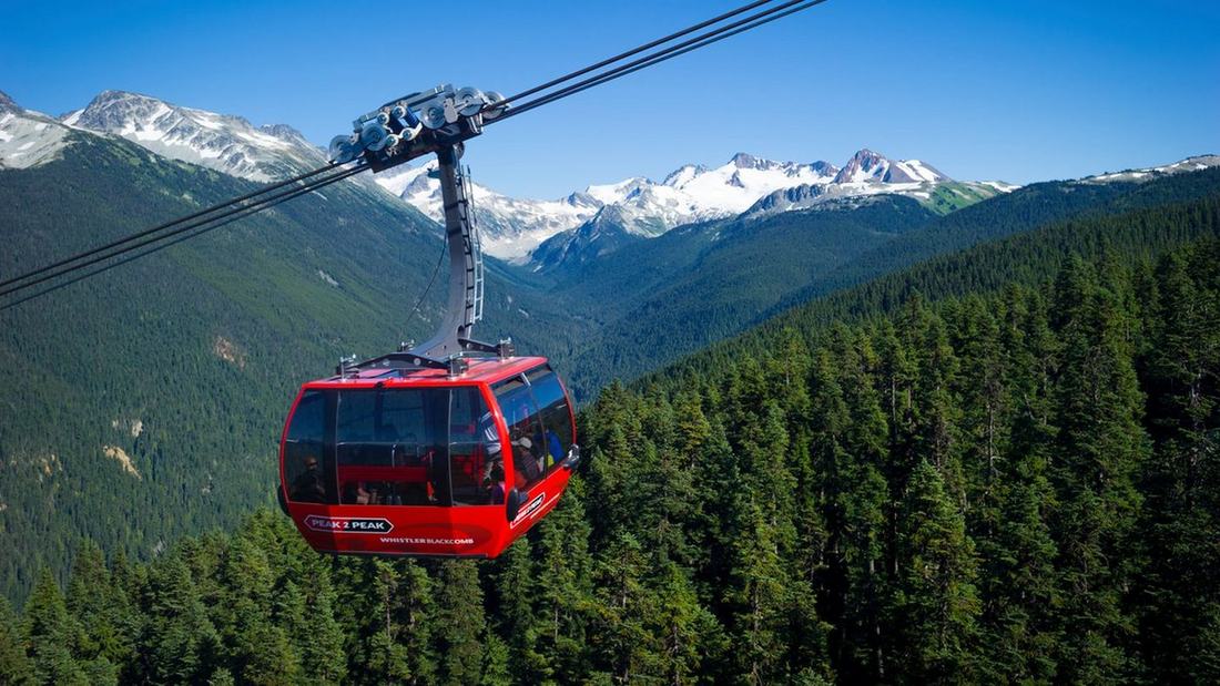 Une cabine rouge de la gondole Peak 2 Peak, entre Whistler et Blackcomb, au-dessus de la forêt en été