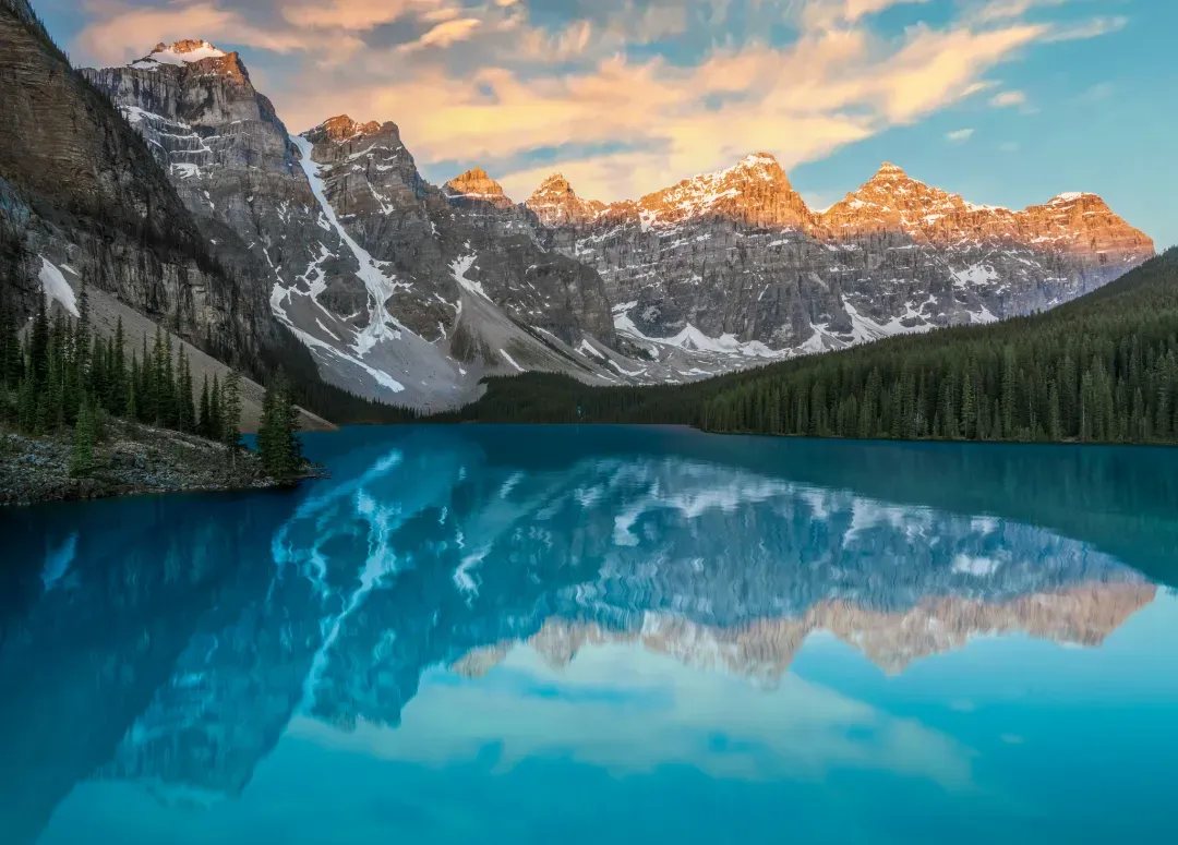Le lac Moraine au lever du jour : l'eau turquoise et la vallée des Dix Pics reflétée dans le lac