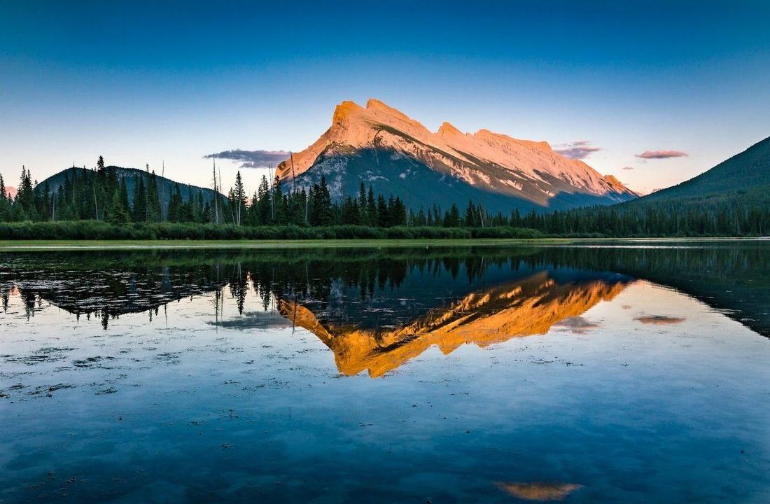 Les lacs Vermilion au coucher du soleil : le mont Rundle doré, reflété dans l'eau, à quelques minutes du camping
